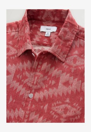 Chemise à motifs rouges avec col, patte de boutonnage, et un design géométrique dans des teintes plus claires de rouge et de beige. Fabriquée en tissu respirant.