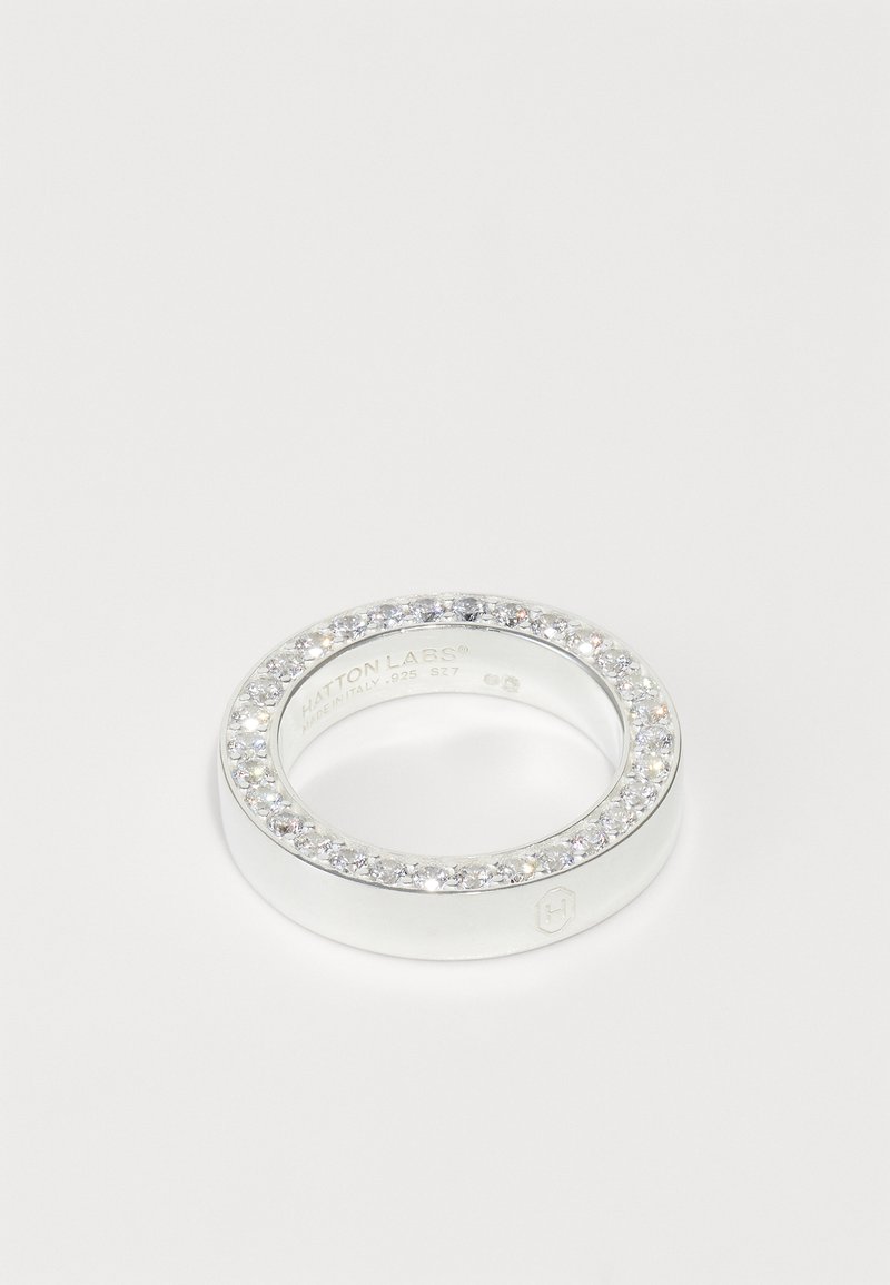 Anillo de plata con una banda lisa y una fila de piedras preciosas redondas y transparentes incrustadas en ella, que reflejan la luz con un acabado pulido.
