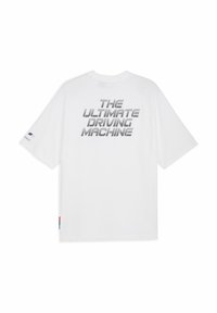 Vit T-shirt med texten "DEN ULTIMATA KÖRANDE MASKINEN" tryckt i grått på baksidan, med färgglada detaljer på ärmarna.