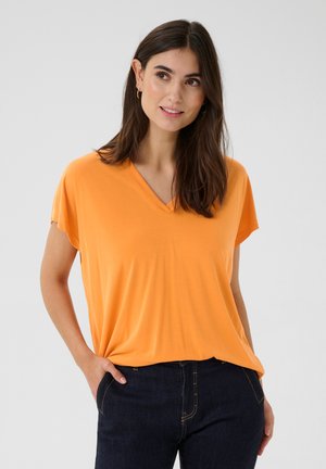 Orange v-neck t-shirt with short sleeves and a relaxed fit, made from soft fabric. Paired with dark denim jeans.