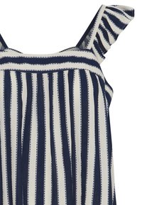 Haut sans manches à rayures bleu marine et blanches avec bretelles à volants, présentant des lignes verticales et des coutures décoratives le long des coutures.