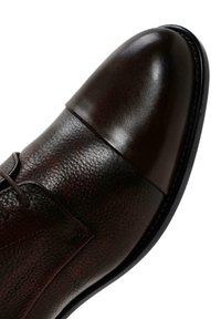 Zapato de vestir de cuero marrón con puntera lisa y lados texturizados, con cordones y una suela elegante. Diseño elegante con costuras mínimas.