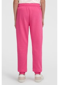 Svetlo roza trenirke z elastičnim pasom in manšetami, izdelane iz mehke tkanine. Oblikovanje vključuje sproščen kroj in gladko teksturo.