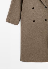 Bruine wolmixjas met een recht gesneden ontwerp, dubbele knopen aan de voorkant en zwarte knopen. Soepele textuur zonder patronen.