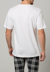 Camiseta de algodón blanca de manga corta y cuello redondo. Tejido texturizado, corte relajado, sin gráficos ni patrones visibles.
