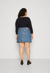 Denim svārki ar izplūdušu formu, gaiši zila krāsa un divas aizmugurējās kabatas. Apvienoti ar melnu garām piedurknēm topu un melnām blokveida papēžiem.