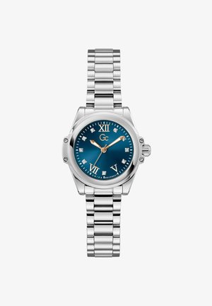 Hõbedane metallkell sinise sihvardiga, Rooma numbrite ja teemantaktsentidega. Omab tekstureeritud randmeosa ja küljes kroon.