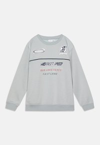 Sudadera gris clara con cuello redondo, que presenta varios logotipos e inscripciones impresas en colores contrastantes, incluyendo acentos en azul marino y rojo.