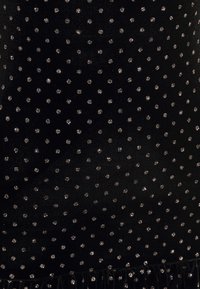 Černá látka zdobená malými, lesklými stříbrnými tečkami, s hladkou texturou a volánkovým lemem na spodní straně.