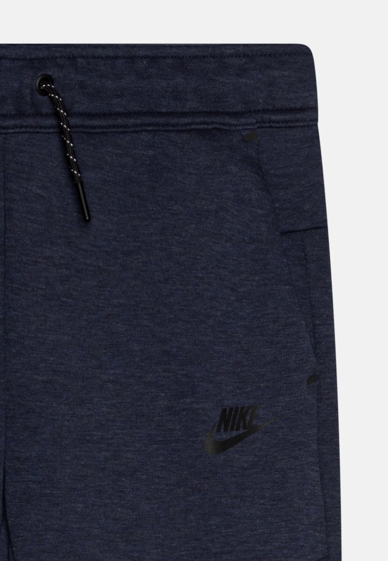 Pantaloni della tuta blu navy con una finitura texture, caratterizzati da un logo Nike nero e un cordoncino regolabile con hardware nero.