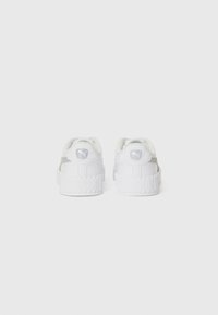 White sneakers with a textured rubber sole, smooth leather upper, and a stitched accent at the heel featuring a logo and padded collar.