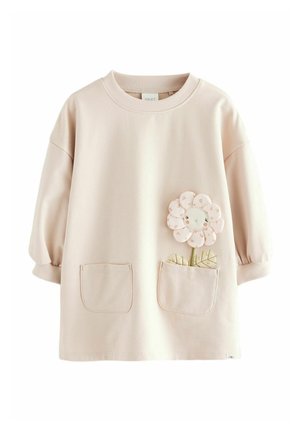 Vestido beige claro de manga larga para niño pequeño, con dos bolsillos delanteros, uno de ellos con una flor rosa sonriente bordada con hojas encima.