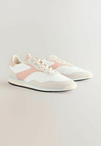 Des chaussures de sport blanches et rose clair, en daim et en mesh, avec une pointe arrondie, un laçage à l'avant et une semelle en caoutchouc noire.