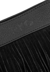Bolso de ante negro con detalles de flecos. La parte superior cuenta con una correa de cuero negro texturizado con el embosado de "RKO". Textura suave y lisa en todo el bolso.