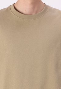 Beige színű pulóver kerek nyakkivágással, puha tapintással és sima anyaggal. Nincsenek minták vagy grafikák. Egyszerű, minimalista dizájn.