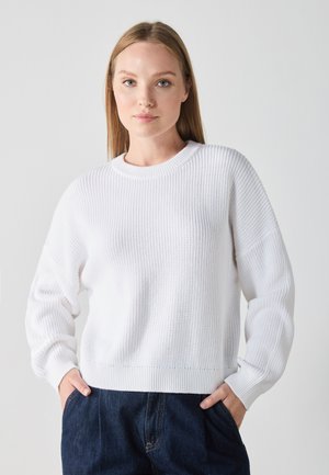 Pulover alb tricotat cu model în dungi, cu guler rotund și croială ușor supradimensionată. Dispune de mâneci lungi și un material texturat, moale.