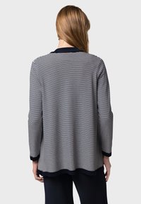 Randig stickad topp med marinblå och vita horisontella ränder, långa ärmar och rund halsringning med kontrasterande kant. Mjuk textur.