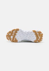 Shoe sole featuring a white base with a wavy pattern and brown rubber accents. Textured surface for grip and stability.