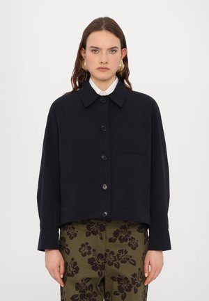 Veste cropped bleu marine en tissu lisse, dotée d'un col, de boutons devant et d'une poche poitrine unique. Assortie à un pantalon à motifs.