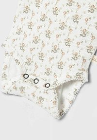 Rebrast beli bodysuit za dojenčke z cvetličnim vzorcem v pastelno roza in zeleni barvi, ki ima črne zaponke in valovite robove.
