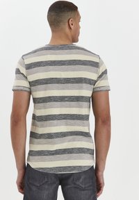 Camisa de manga corta a rayas con rayas horizontales en gris y crema, textura suave, cuello redondo y dobladillo curvado.