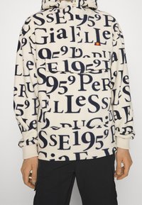 Sudadera de forro polar con capucha, color crema, que presenta grandes patrones de texto en azul oscuro. Incluye un bolsillo frontal y puños acanalados.