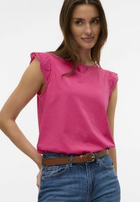 Roze katoenen mouwloze top met kantaccenten op de schouders, gecombineerd met high-waisted denim jeans en een brown leren riem.
