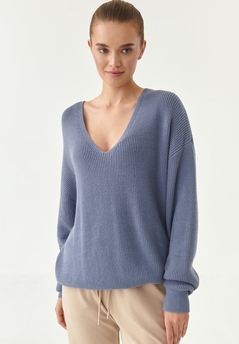 Maglione azzurro chiaro lavorato a maglia con scollo a V profondo, maniche lunghe e texture a coste. Il tessuto morbido scivola liberamente sul corpo.