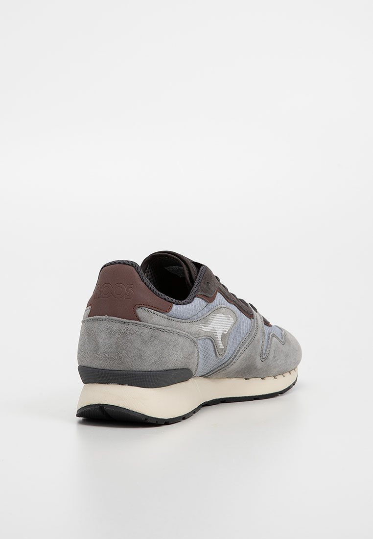 Grijze sneaker met een bovenwerk van suede en textiel, donkerbruine accenten, een textuurpatroon en een gevoerde zool voor comfort en ondersteuning.