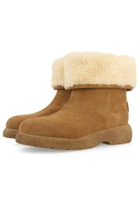 Botas de tobillo de ante color arena con un puño de piel sintética color crema y suela texturizada color marrón claro. Punta redonda y diseño corto y robusto.
