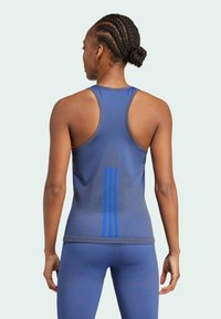 Top deportivo azul sin mangas con diseño de espalda nadadora, que presenta una tela texturizada y tres franjas verticales azules en la parte posterior.
