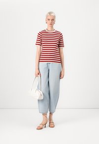 T-shirt in cotone a righe rosse e bianche, jeans a gamba larga azzurri, scarpe con tacco a strappo beige e una borsa strutturata bianca. Design minimalista.