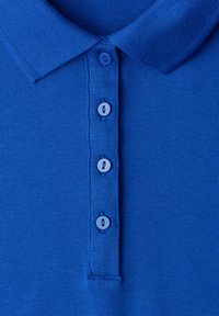 Polo en maille bleu avec quatre boutons bleus assortis et un col côtelé.