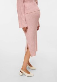 Lyserød ribbet strikket kjole med lange ærmer og sideslids, parret med crème farvede slingback-sko med en sløjfe og blokhæl.