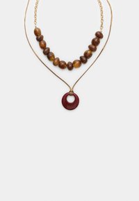 Collana a strati con una catena dorata, una lunghina di perline marroni e un pendente circolare bordeaux con un ritaglio centrale.