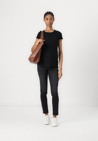 Brun skinn totebag, stripete svart topp, smale svarte jeans og hvite joggesko. Enkel design med en naturlig finish og subtile detaljer.