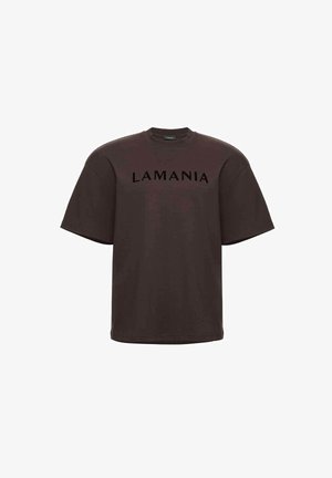 Rudi medvilniniai marškinėliai su laisvu siluetu, su apvalia apykakle ir trumpomis rankovėmis. Ant krūtinės juodai užrašyta „LAMANIA“.