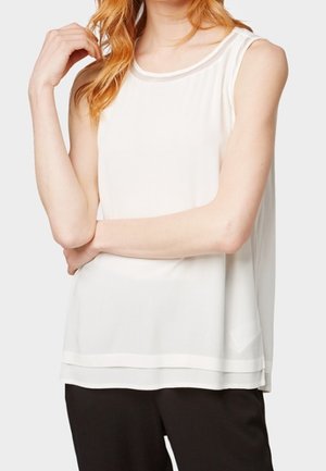 Hvid ærmeløs top med rund halsudskæring, der har en gennemsigtig tekstur og lagdelt kant. Stoffet er let med en glat finish.