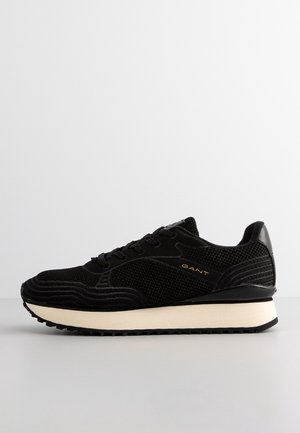 Sneaker in rete nera e suede con suola spessa beige, design con lacci e logo "GANT" sul lato.