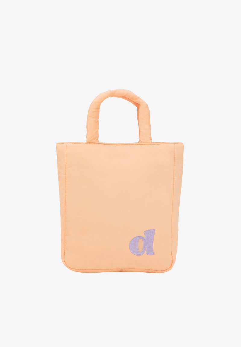 Peachfärgad toteväska med quiltat tyg, två handtag och ett lila broderat bokstaven "d" i det nedre hörnet. Slät textur.