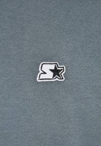 Maglietta in cotone grigio con logo ricamato in contorno nero e una stella, posizionata al centro sul davanti per un dettaglio visivo.