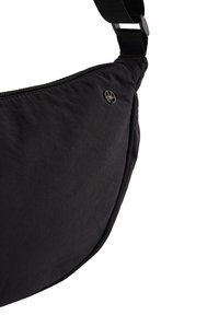 Črna torbica za čez ramo z teksturirano tkanino, opremljena z zadrgo in okroglim logotipom. Ima nastavljiv trak za udobje.