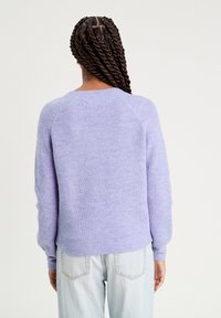 Lavendel gebreide trui met een ribbeltextuur, ronde halslijn en raglanmouwen. De achterkant is glad, aangevuld met aansluitende zomen.