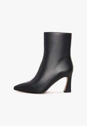 Stivale alla caviglia in pelle nera con punta affusolata e tacco curvo di altezza intermedia su sfondo bianco.