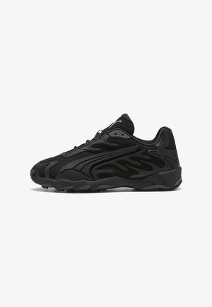 Chaussure de sport noire avec une tige en mesh texturé, présentant un design synthétique incurvé, une semelle épaisse et des détails de marque minimaux.