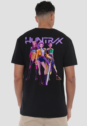 Black t-shirt featuring a colorful graphic on the back with three stylized characters and the text "HUNTRX" in purple above them.