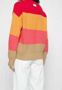 Strickpullover mit horizontalen Streifen in Rot, Orange, Pink und Beige. Strukturierter Stoff und gerippte Bündchen sowie Saum. Quadratisches Etikett auf der Rückseite.