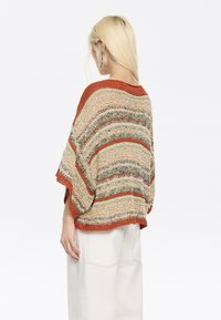 Mehrfarbiger gestrickter Pullover mit lockerer, übergroßer Passform. Merkmale horizontale Streifen in erdigen Tönen wie Rost, Grün und Beige. Rippensaum.