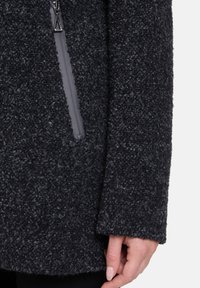 Ciemnoszary, teksturowany płaszcz z miękkiego, puszystego materiału, z czarnym zamkiem błyskawicznym i smukłą kieszenią z boku.