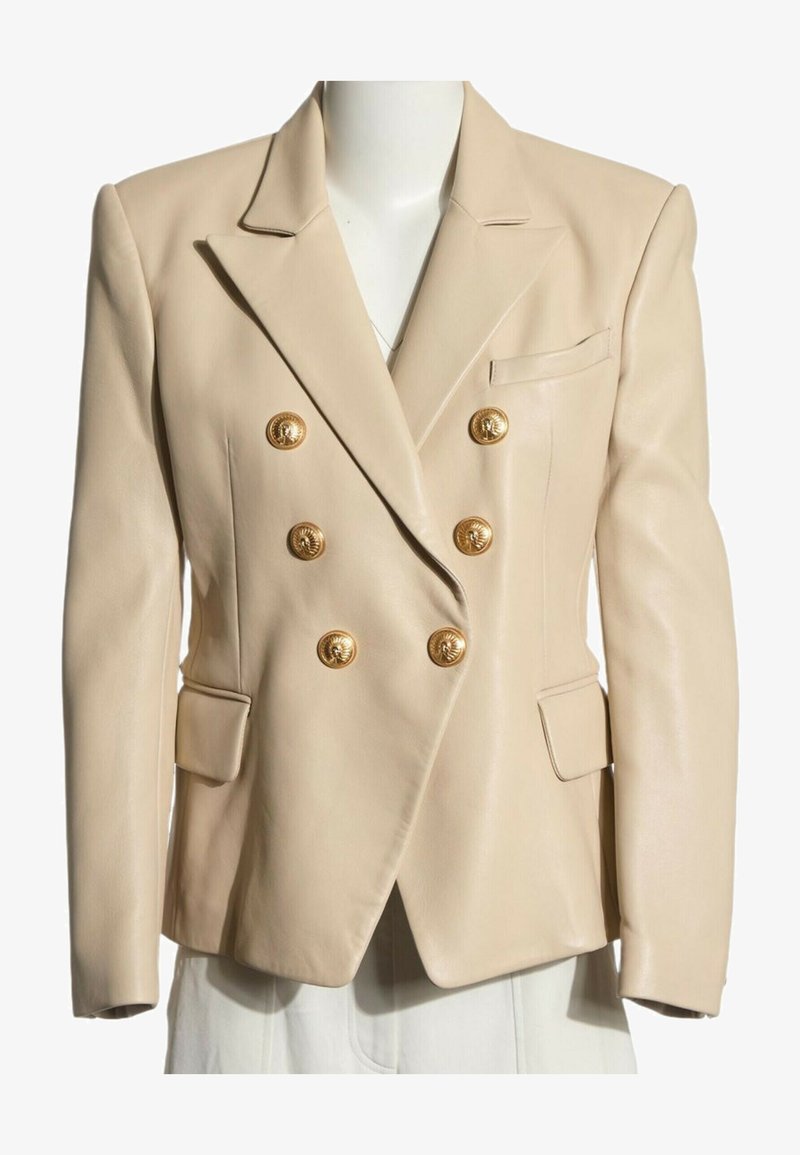 Blazer beige à double boutonnage avec six boutons décoratifs dorés et deux poches à rabat avant sur un buste de mannequin.